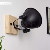 Black wall lamp with wooden base on a white wall, brand 'hofstein' visible